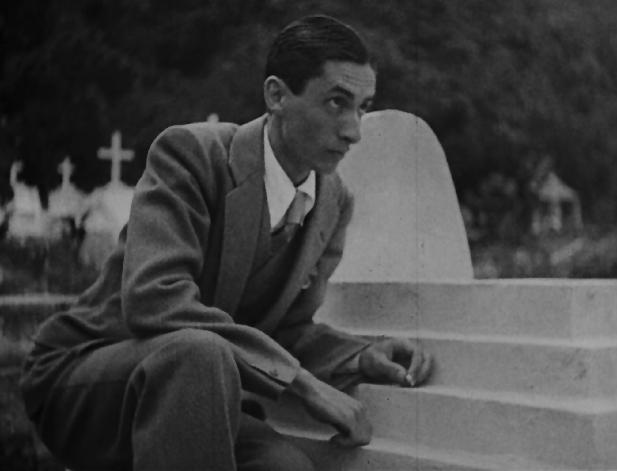 Illustration from the novel theMystery.doc by Matthew McIntosh. Black-and-white still from the film "Limite" showing a slim, dark-haired man in a cemetery. He is wearing a suit and tie, and reclining against the carved stone steps of a grave.